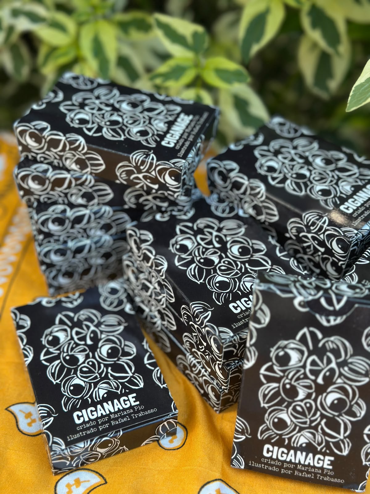 Pilhas de caixas do baralho Ciganage sobre pano amarelo estampado